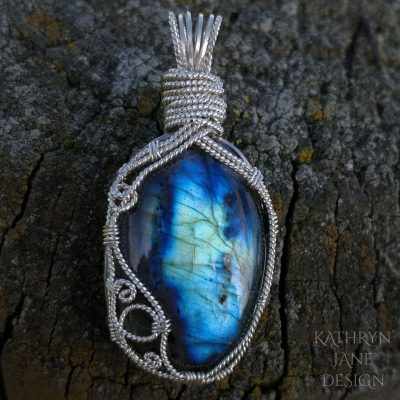 Blue 'sea scene' labradorite with central support and waves swelling at the side.