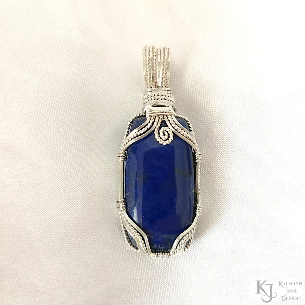 On this oblong-shaped lapis lazuli, a secure but open support is provided by the sterling silver framework, with front design consisting of square wires either side of a central twisted silver strand. The top spiral provides decoration, as well as symbology for growth.
