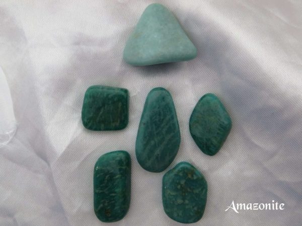 Amazonite Amazonite tumbled gemstone crystals. Turquoise-coloured stones of different shapes. White satin background.