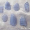 Blue lace agate Blue lace agate, polished freeform gemstone crystal shapes. Lilac blue in colour, and opaque, with bands of darker blue and transparency. White satin background.