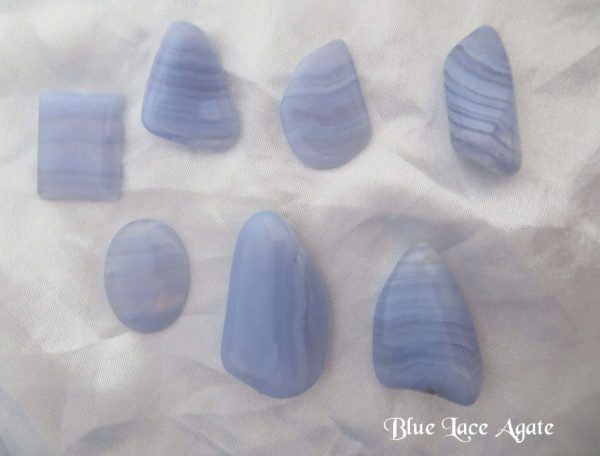 Blue lace agate Blue lace agate, polished freeform gemstone crystal shapes. Lilac blue in colour, and opaque, with bands of darker blue and transparency. White satin background.