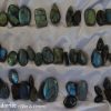 Labradorite cabochons. Large selection which is constantly being replenished. Many labradorite gemstone crystal cabochons, in various shapes and colours of blue and green. White satin background.