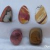 Mookaite, Australia Mookaite gemstone crystals from Australia. Two pear-shaped cabochons and three free-form shaped tumbled and polished stones. Opaque, warm earthy colours of orange, brown, dusky pink, yellow ochre and white. White satin background.