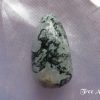 Tree agate Tree agate gemstone crystal. Tumbled oblong stone, white quartz appearance with growths of dark green throughout. White satin background.