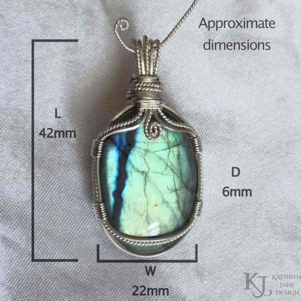 Flashy green, oval labradorite gemstone crystal pendant, lovingly handcrafted into a pendant with sterling silver wire. Twisted wire spiral at top centre. White satin background. Approximate measurements, 42mm long, 22mm wide, 6mm deep