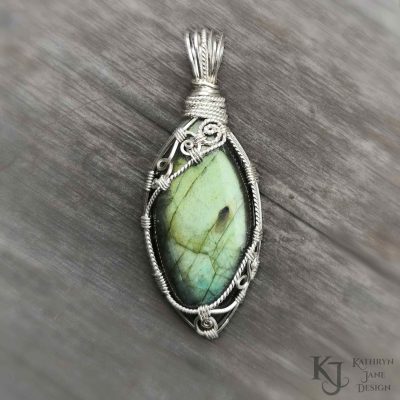 Fine, ornate spirals adorn the top and bottom of this vesica piscis-shaped labradorite, securely holding the stone in place.