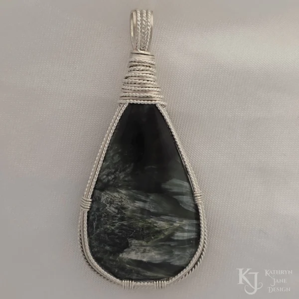 Dark green seraphinite, natural stone, teardrop-shaped pendant, wire-wrapped in twisted sterling silver wire in a simple, outer framework, by Kathryn Jane Design. Plain white background.