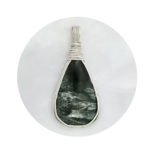 Pear-shaped seraphinite stone pendant in sterling silver wire framework on light background. White frame with circle cutout showing pendant in the middle