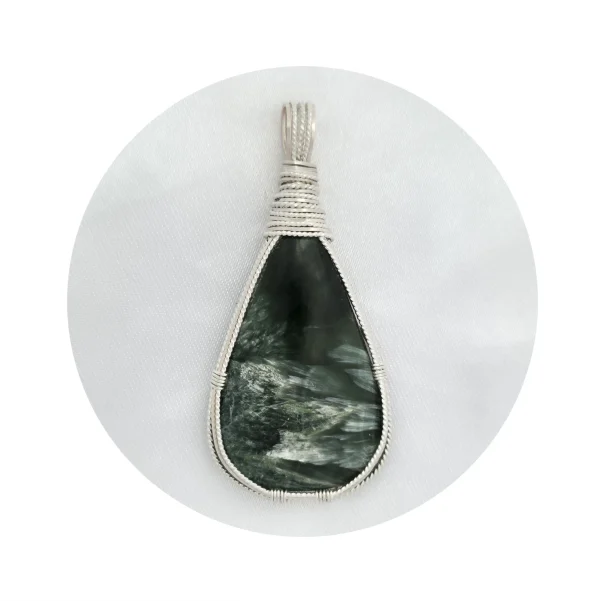 Pear-shaped seraphinite stone pendant in sterling silver wire framework on light background. White frame with circle cutout showing pendant in the middle