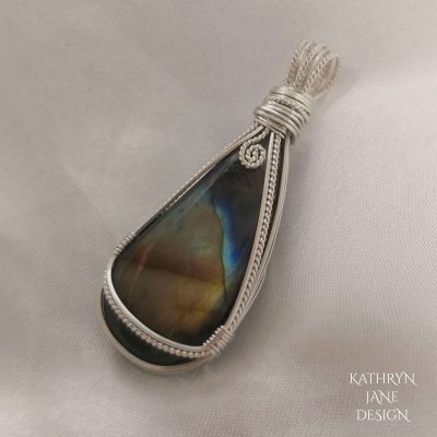 Curved teardrop labradorite gemstone pendant, with striking gold and blue flash. Looks like desert sands with midnight sky above, with a full moon constructed by spiral of twisted silver.