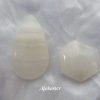 Alabaster Alabaster gemstone crystal, white cabochons, one a peardrop shape with horizontal bands of various shades of white running through, the other a hexagon. White satin background.