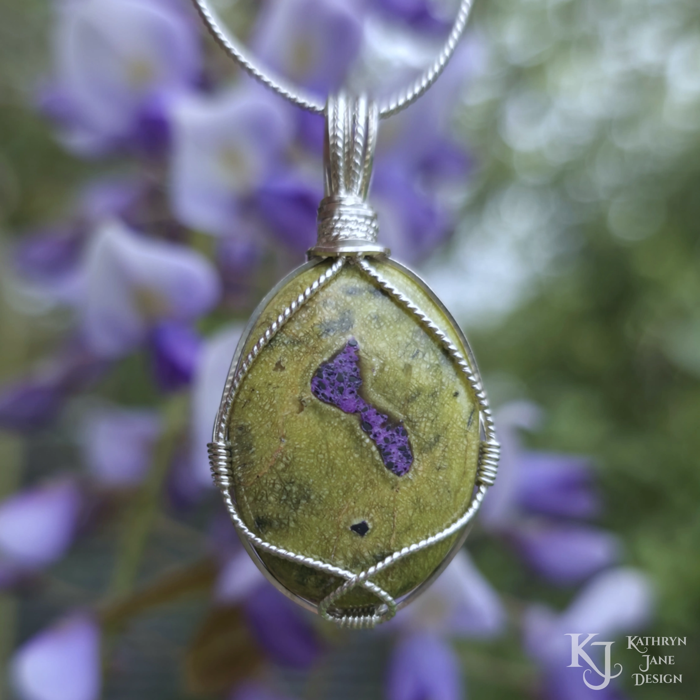 Kathryn Jane Design wire-wrapped Atlantisite pendant with sterling silver forming a framework. Purple stichtite in the middle of the green serpentine. Purple and green background