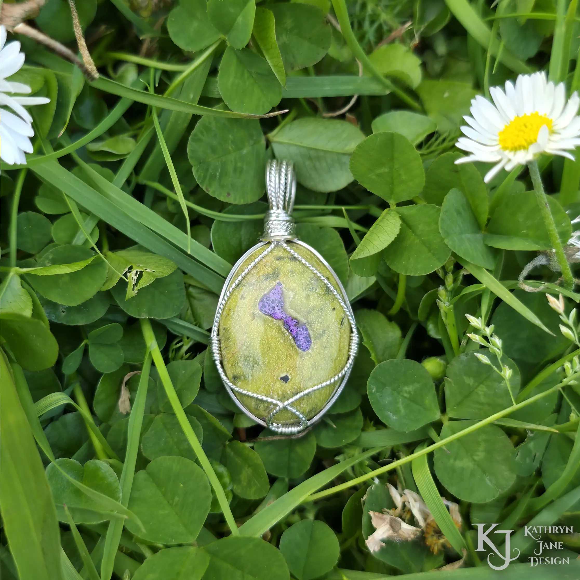 Kathryn Jane Design wire-wrapped Atlantisite pendant with sterling silver forming a framework. Purple stichtite in the middle of the green serpentine. Clover and background