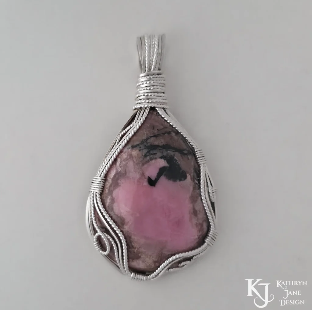 Wire-wrapped Kathryn Jane Design sterling silver rhodonite pendant on white background