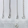Four different types of necklace chain. One is an oval belcher in sterling silver, the other three are silver-coloured display chains. White painted background.