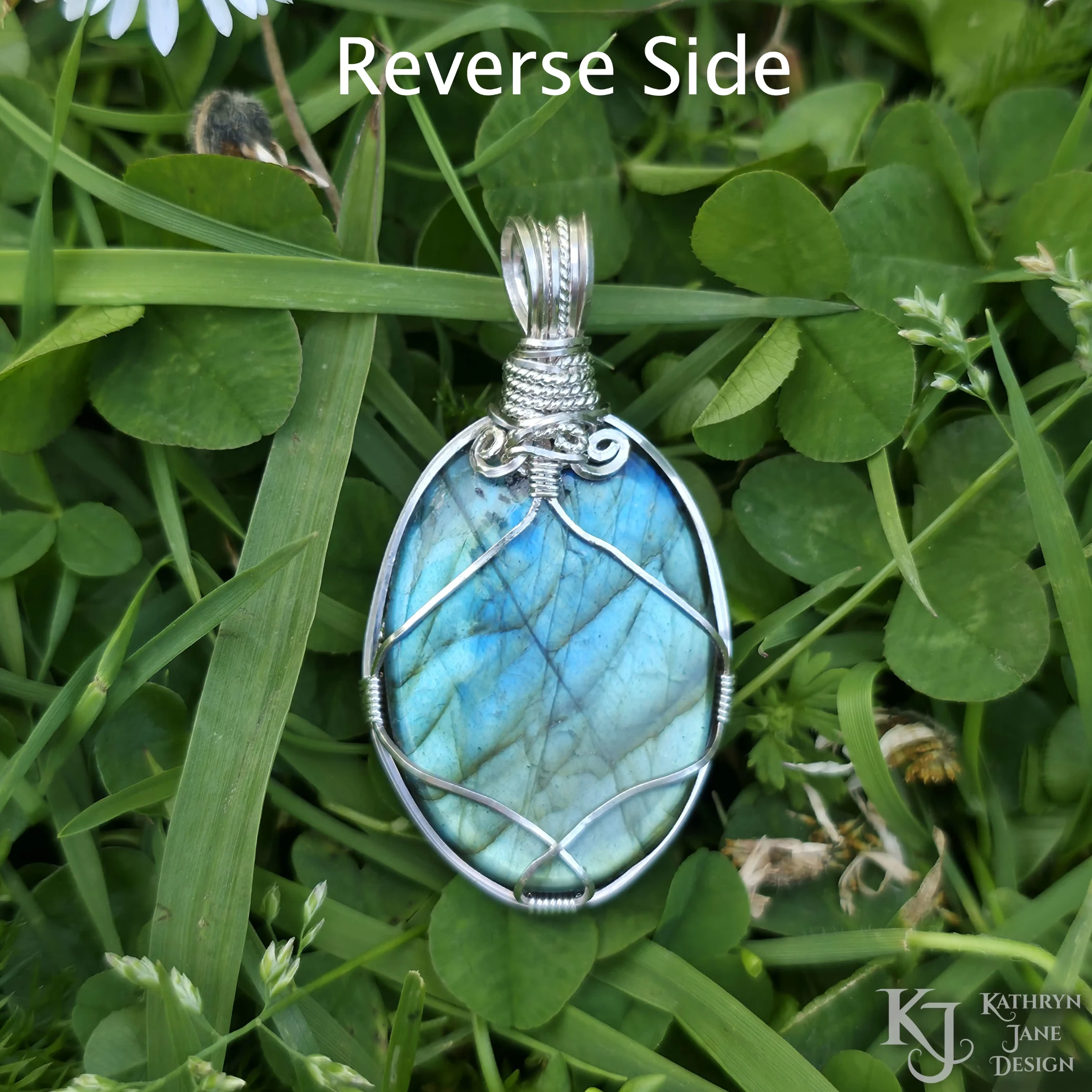 Kathryn Jane Design wire-wrapped labradorite pendant with sterling silver forming a framework. Grass background.