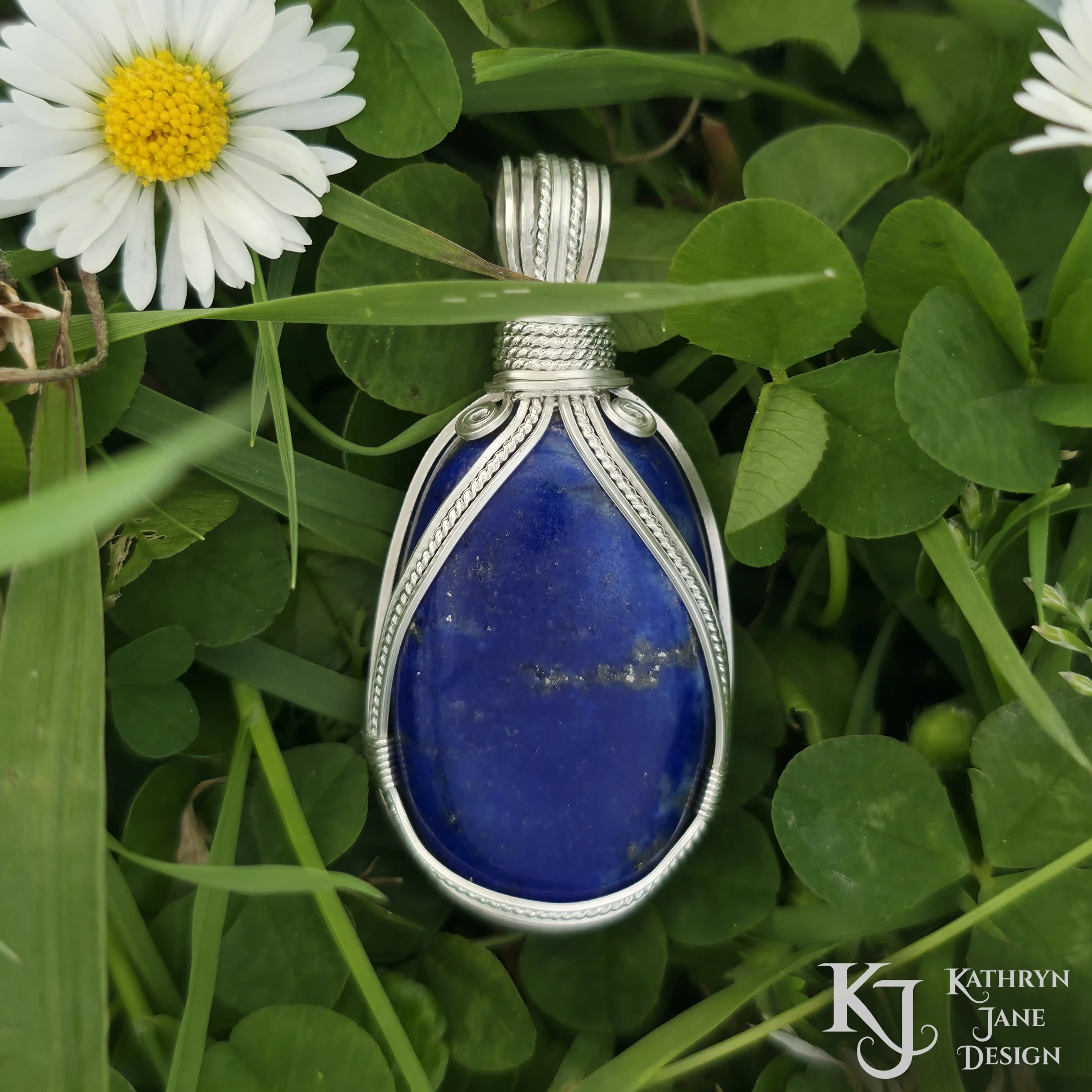 Kathryn Jane Design wire-wrapped lapis lazuli pendant with sterling silver forming a framework. Grass background.
