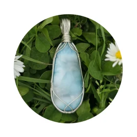 Turquoise-blue larimar pendant, with square and twisted sterling silver wire support and bail by Kathryn Jane Design. Green clover background with two white daisies with yellow centres.