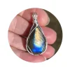 Triangular-shaped natural labradorite pendant in a simple sterling silver framework in hand in bright sunlight. Labradorescence showing brilliant gold and electric blue