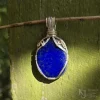 The direct sunlight shows the richness of the blue colouration. See the white calcite shoulder underneath the gold-filled spiral? Oblong-shaped royal blue lapis lazuli pendant with sterling silver and 14k gold-filled wire spirals at the top, and in the bail. Rich royal blue colour visibile in direct sunlight, as well as white calcite shoulder, with Kathryn Jane Design logo in the bottom right
