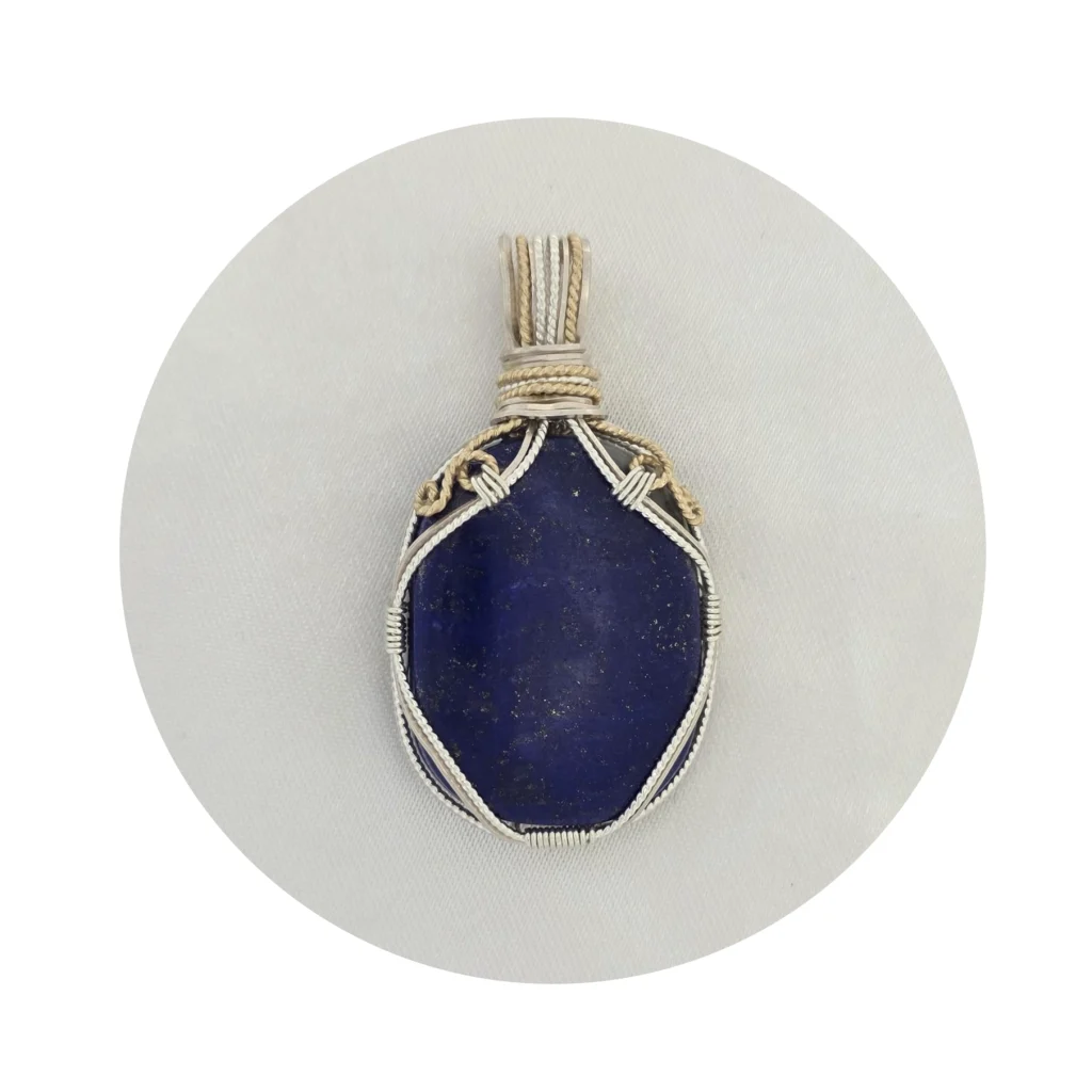 Oblong-shaped royal blue lapis lazuli pendant with sterling silver and 14k gold-filled wire spirals at the top, and in the bail. White background