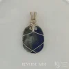 Photo taken in filter cone, showing reverse side. Lazurite, pyrite and calcite visible Rever side of oblong-shaped royal blue lapis lazuli pendant with sterling silver and 14k gold-filled wire spirals at the top, and in the bail. White satin background with Kathryn Jane Design logo in the bottom right