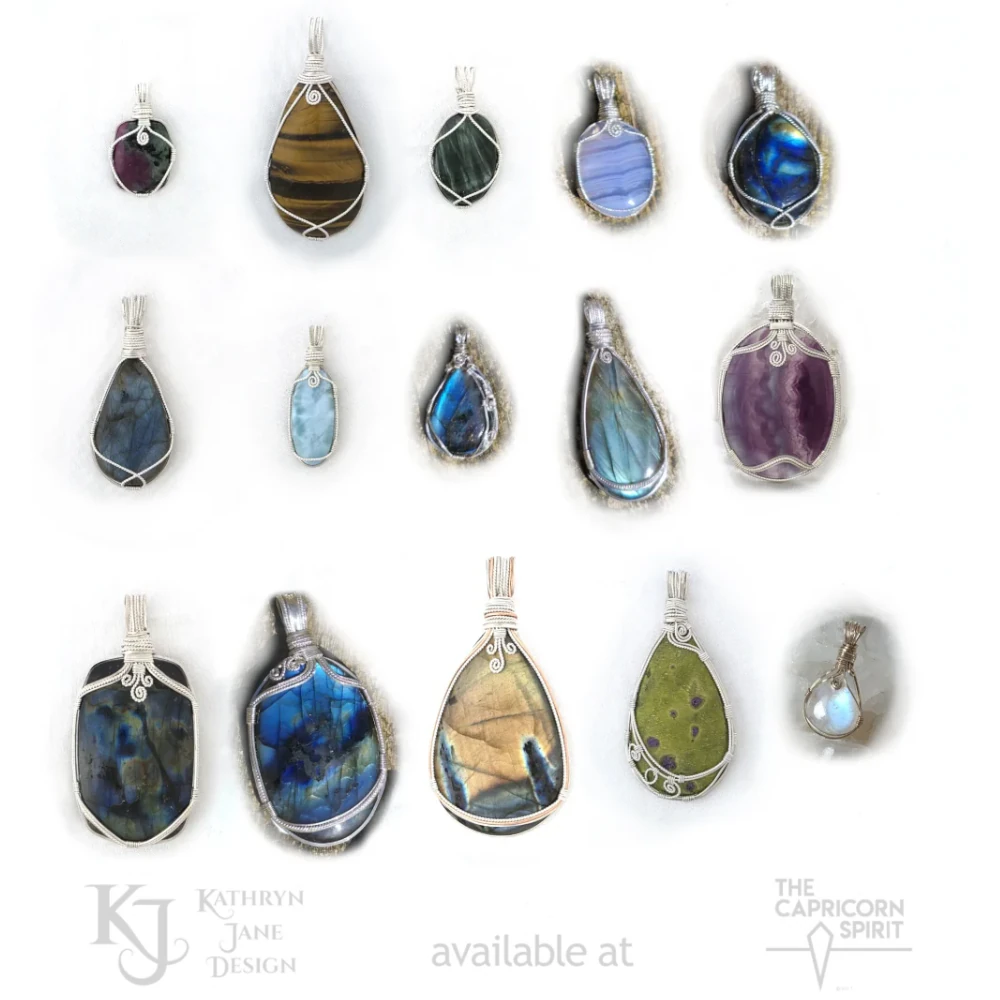 Wire-wrapped labradorite pendants, sterling silver fluorite pendant and 9ct gold rainbow moonstone pendant plus other varieties of handcrafted pendant on a white satin background. Kathryn Jane Design pendants available at The Capricorn Spirit